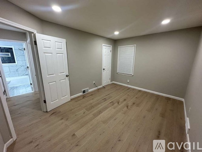 A room with wooden flooring and two white doors.