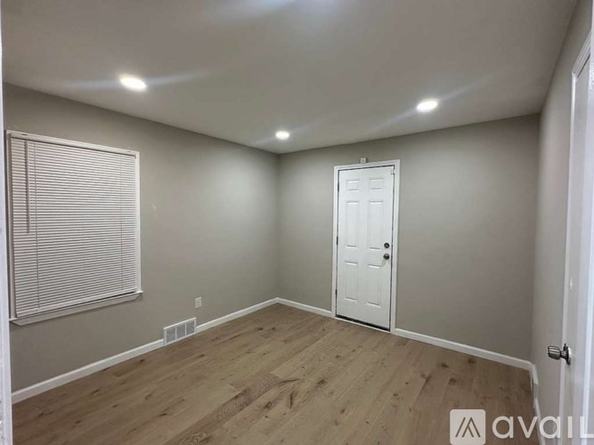 A room with a white door and a window with blinds.