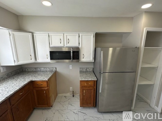 A kitchen with white cabinets and a stainless steel refrigerator.