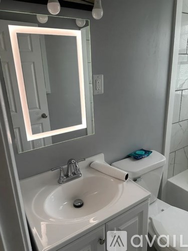 A bathroom with a sink, toilet and mirror.