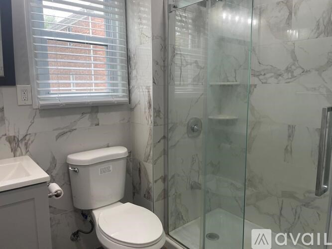 A white toilet sits next to a glass shower stall in a bathroom.