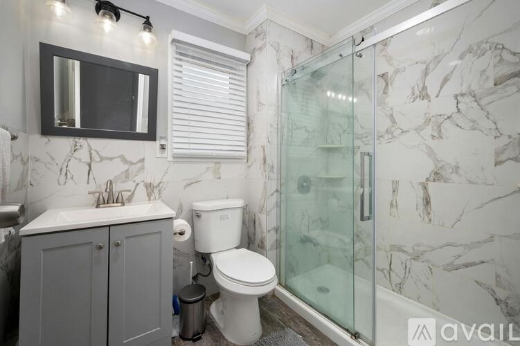 A bathroom with a marble wallpaper and a glass shower stall.