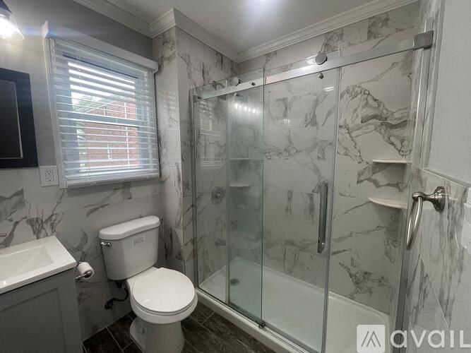 A bathroom with a marble wall and a glass shower stall.