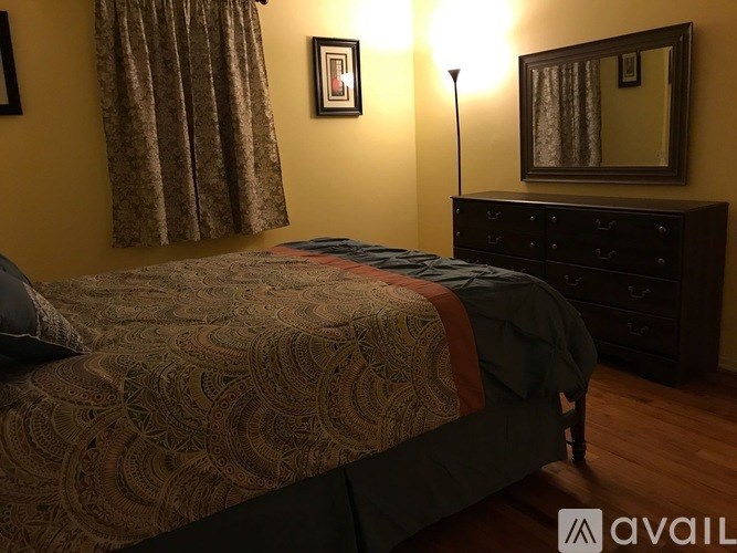 A bedroom with a bed, dresser, and mirror.