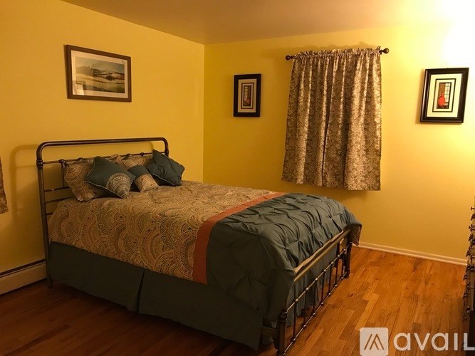 A bedroom with a bed, pillows, and pictures on the wall.