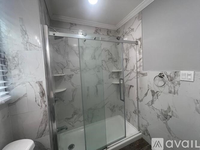 A bathroom with a marble patterned shower and toilet.