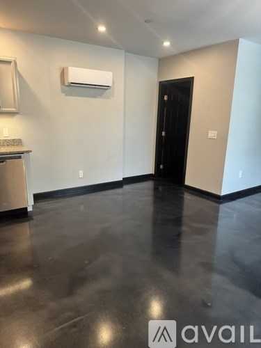 A room with a black door and a wall-mounted air conditioner.