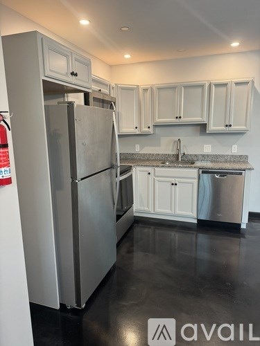 A kitchen with a black floor and white cabinets.