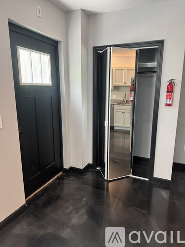 A black door with a window and a white wall.