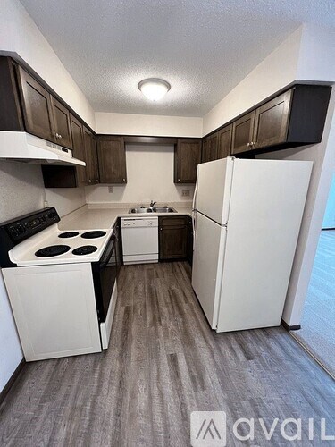 A kitchen with white appliances and brown cabinets.
