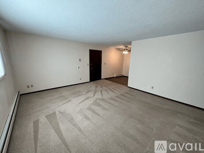A room with a carpeted floor and a door in the background.