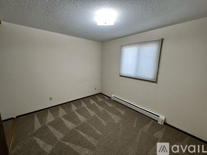 A room with a carpeted floor and a window with blinds.