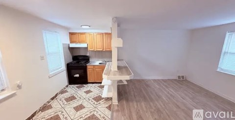 A kitchen area with wooden cabinets and a black fridge.