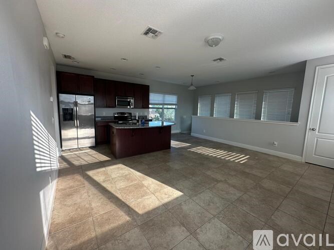 A spacious kitchen and living room with tiled flooring and a large island.