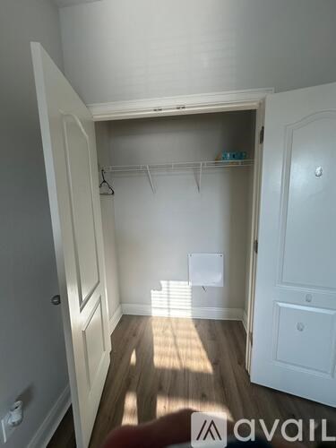 A white closet with a wooden floor and a white door.