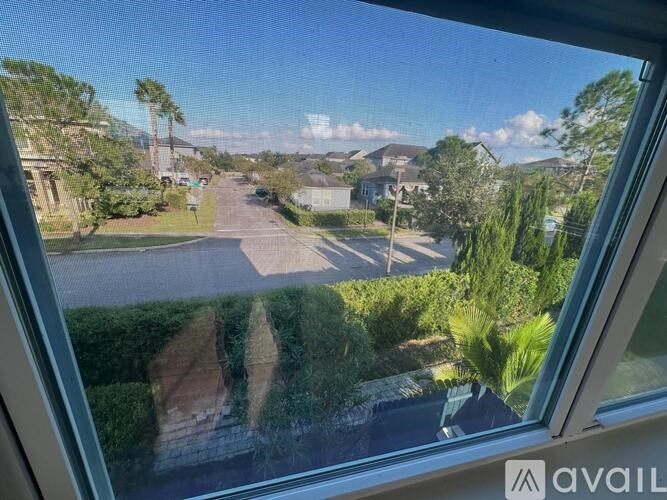 A view from inside a room looking out onto a street with houses and trees.