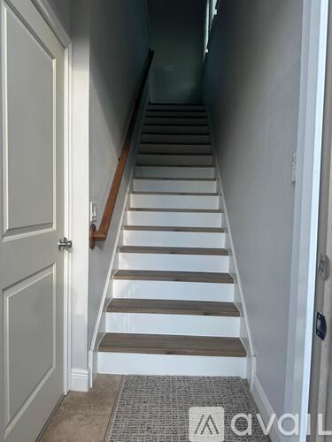 A hallway with a staircase and a door on the left.