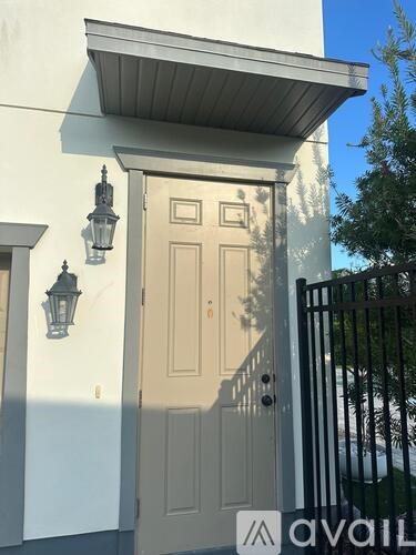 A white house with a beige door and a black gate.