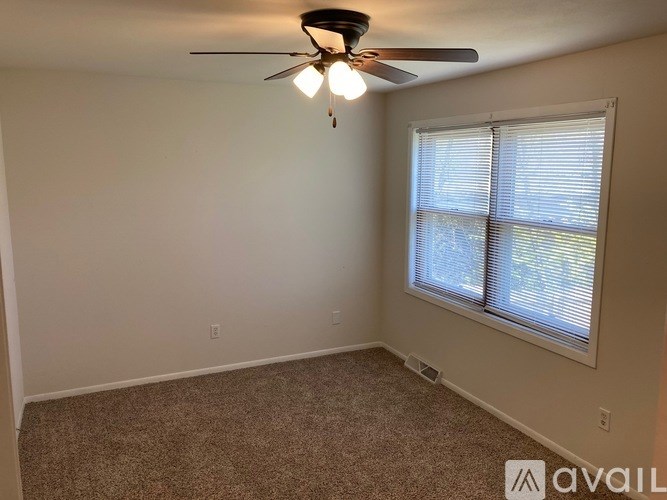 A room with a ceiling fan and carpeted floor.