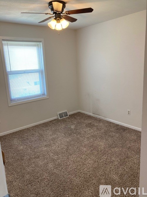 A room with a ceiling fan and carpeted floor.
