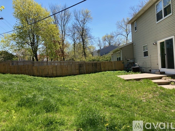 A backyard with a wooden fence and a house in the background.