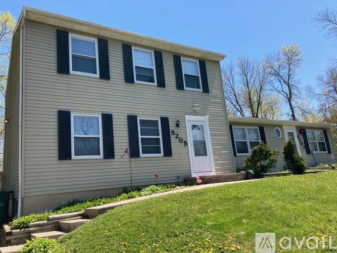 A beige house with black shutters and a white door.
