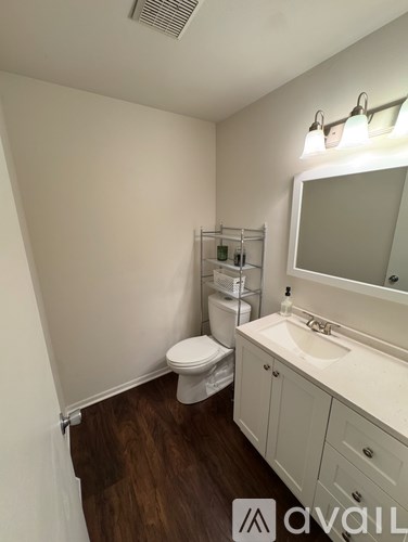 A bathroom with a toilet, sink, and mirror.
