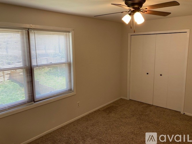 A room with a ceiling fan and a window with blinds.