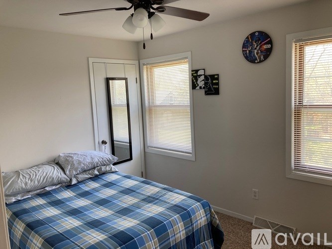 A bedroom with a bed, a ceiling fan, and a mirror.