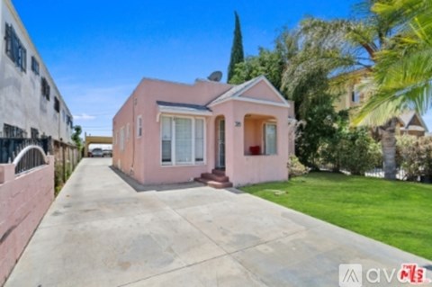 A pink house with a white fence and a green lawn in front.