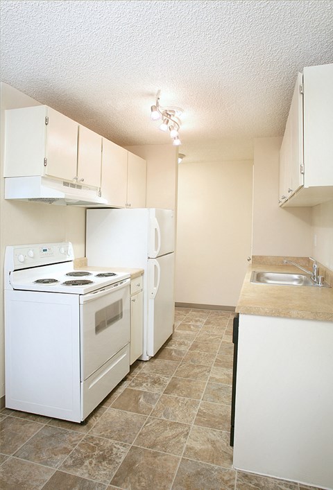an empty kitchen with a stove refrigerator and sink