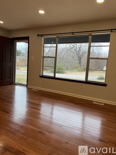 A room with wooden flooring and a large window.