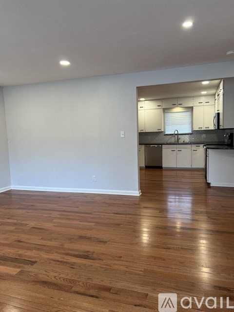 A kitchen with white cabinets and a wooden floor.