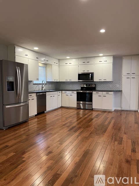 A kitchen with wooden floors and white cabinets.