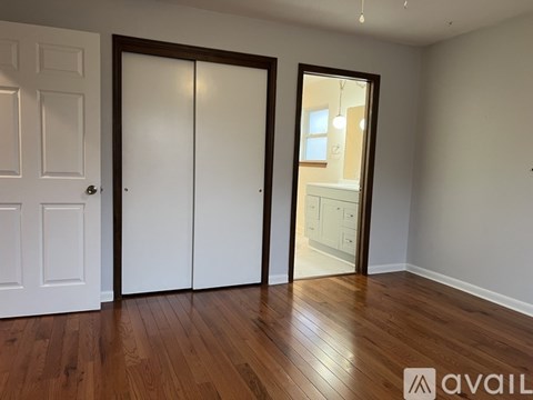 A room with a white door, a white wardrobe, and a wooden floor.