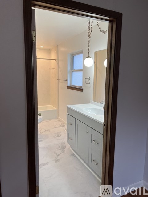 A bathroom with a mirror, sink, and cabinets.