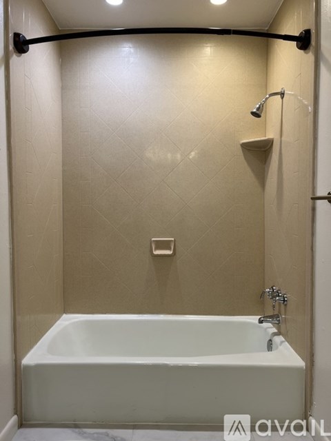A bathroom with a white tub and a shower head.