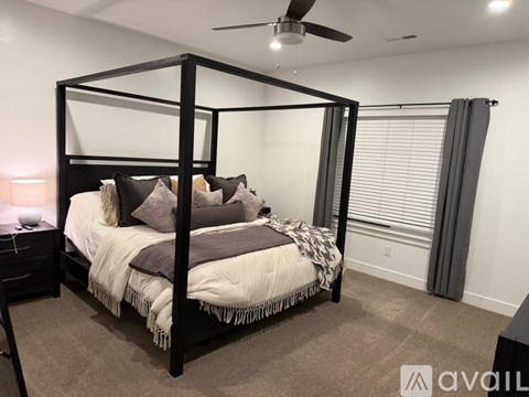 A bedroom with a four-poster bed and a ceiling fan.