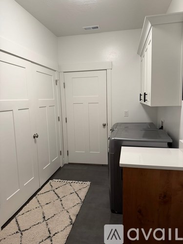 A kitchen with white cabinets and a black and white rug on the floor.