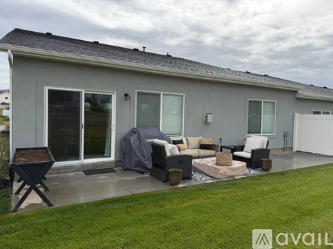 A grey house with a patio and a black chair.