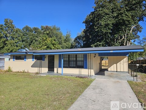 A small building with a blue roof and white walls is surrounded by greenery.