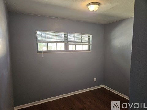 A room with a window and wooden flooring.