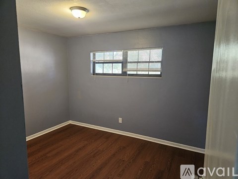A room with a window and wooden flooring.