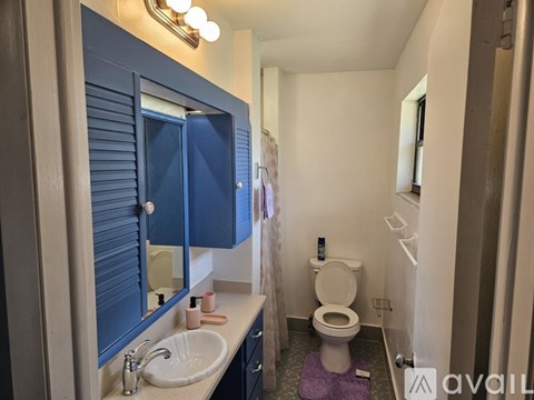 A bathroom with a toilet, sink, and mirror.