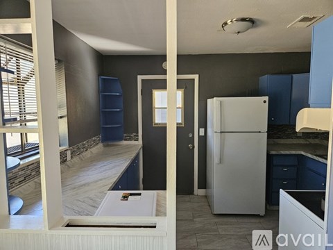 A kitchen with a white fridge and a doorway leading to another room.