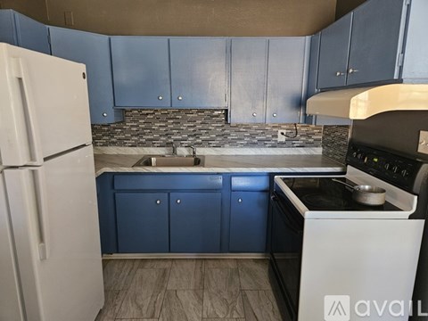 A kitchen with blue cabinets and a white refrigerator.