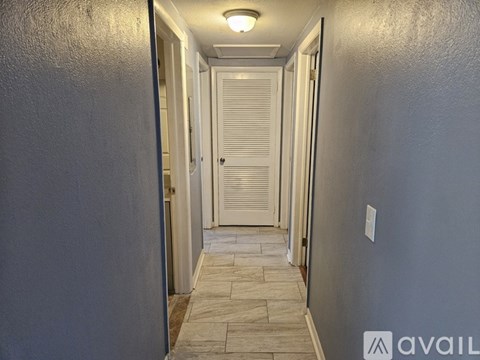 A hallway with a closed door and a light on the ceiling.