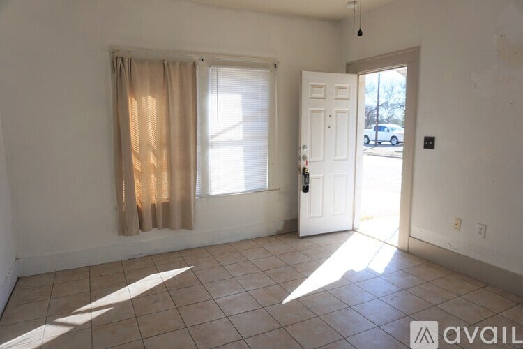 A room with a door and a window with curtains.