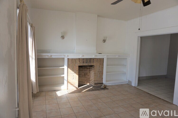 A room with a fireplace and a fan on the ceiling.