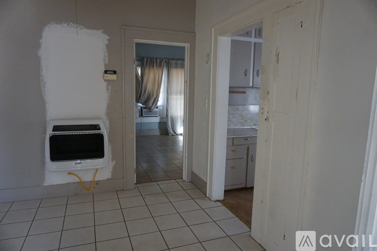 A room with a white tiled floor and a white wall with a hole in it.